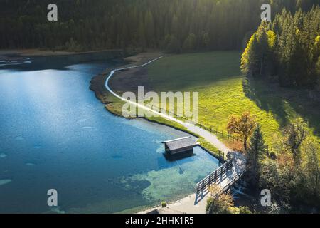 Luftlandschaft von kleinen Hütten auf grünen grasbewachsenen Hang des Berges in der Nähe von ruhigen See von Nadelwald an sonnigen Tag umgeben Stockfoto