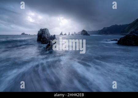 Mächtiges Meer mit harten felsigen Klippen inmitten von Hangbergen gegen bewölkten Himmel in der Natur Spaniens Stockfoto