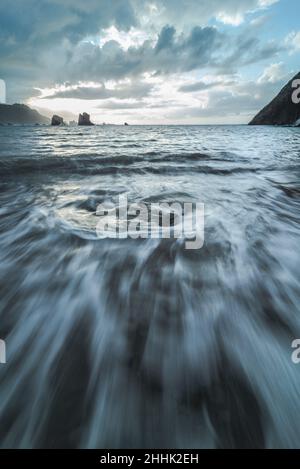 Mächtiges Meer mit harten felsigen Klippen inmitten von Hangbergen gegen bewölkten Himmel in der Natur Spaniens Stockfoto