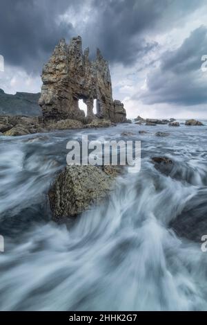 Mächtiges Meer mit harten felsigen Klippen inmitten von Hangbergen gegen bewölkten Himmel in der Natur Spaniens Stockfoto