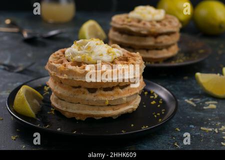 Optimistische junge hispanische Frau mit lockigen dunklen Haaren lächelt, während sie Gesichtsmassage mit einem Gua Sha-Werkzeug vor weißem Hintergrund macht Stockfoto