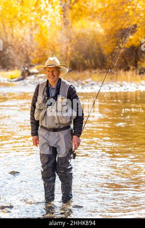 USA, Idaho, Bellevue, Porträt eines lächelnden älteren Mannes Fliegenfischen in Big Wood River im Herbst Stockfoto