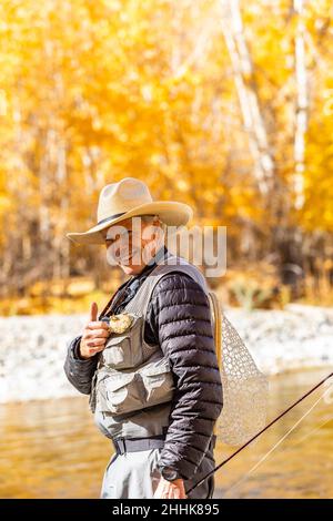 USA, Idaho, Bellevue, Porträt eines lächelnden älteren Mannes Fliegenfischen in Big Wood River im Herbst Stockfoto