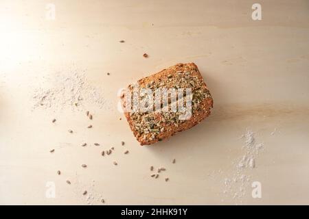 Vollkornbrot mit Samen und Körnern auf einem Holztisch von oben, großer Kopierraum in alle Richtungen, hohe Winkelansicht, ausgewählter Fokus, schmale Abschrägung Stockfoto