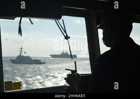 220122-N-EF547-1009 PHILIPPINISCHES MEER (JAN 22, 2022) Ensign Nate Kader, ein gebürtiger Brynn Mawr, Penn., steht mit einem konnenden Offizier an Bord des Ticonderoga-Klasse Raketen-Kreuzers USS Lake Champlain (CG 57), 22. Januar 2022. Als Teil der US-Pazifikflotte führen Einheiten, die Carl Vinson und Abraham Lincoln Carrier Strike Groups, America und Essex Amphibious Ready Groups, zusammen mit der japanischen Maritime Self-Defense Force zugewiesen sind, Schulungen durch, um eine freie und offene Region im Indo-Pazifik zu erhalten und zu schützen. (USA Navy Foto von Ensign Sarah Weinstein Stockfoto