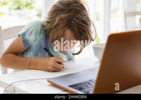 Junge (8-9) beim Zeichnen eines Bildes während des Online-Unterrichts Stockfoto