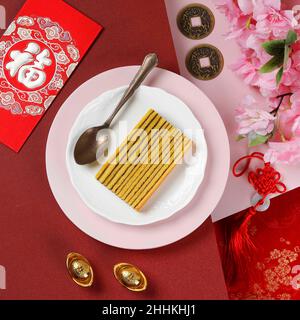 Lapis Legit, traditionelle indonesische tausendschichtige Torte mit chinesischem Neujahrsrot-Konzept. Scheiben auf weißer Platte, Ansicht von oben. Chinesisches Zeichen ist Fu Stockfoto