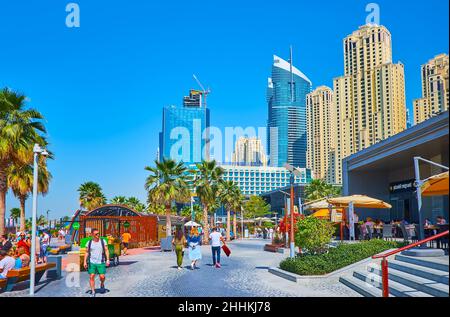 DUBAI, VAE - 7. MÄRZ 2020: JBR Marina Beach Walk mit Palmen, Restaurants, Geschäften und den Wolkenkratzern der Dubai Marina im Hintergrund, am März Stockfoto