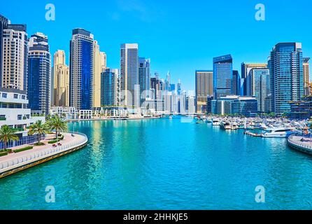 Genießen Sie Dubai Marina von der Brücke aus, mit Blick auf Wolkenkratzer, schwimmende und festfahrende Boote, Promenade mit Palmenallee, Dubai, VAE Stockfoto