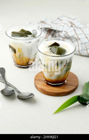 Grünes Grasgelee oder Cincau Hijau im Glas, traditionelles indonesisches Dessert aus Cyclea Barbata-Blatt. Serviert mit Palmzucker-Sirup und Coconut M Stockfoto