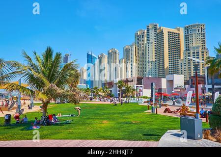 DUBAI, VAE - 7. MÄRZ 2020: Der Rasen am Strand von JBR Marina gegen die hohen Wohnhäuser des Dubai Marina Distrikts, am 7. März in Dubai Stockfoto
