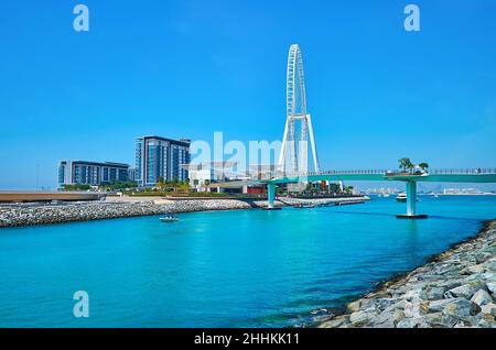 Der Blick auf moderne Luxushäuser auf der Bluewaters Island, Ain Dubai, Riesenrad und Fußgängerbrücke über den schmalen Hafen, Dubai, VAE Stockfoto