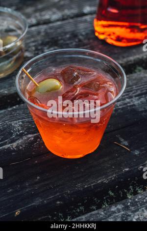 Aperol Spritz in Plastikbecher mit grünen Oliven im Freien Stockfoto