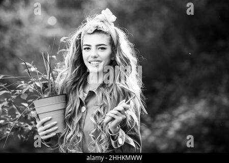 Beauty Frau genießt im Garten mit Blumen. Die Gärtnerin wächst Blumen im Topf. Stockfoto