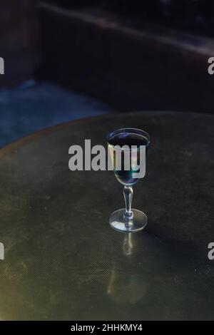 Schillerndes schwarzes Limonade-Cocktailgetränk am Abend mit goldenem Messingtisch Stockfoto