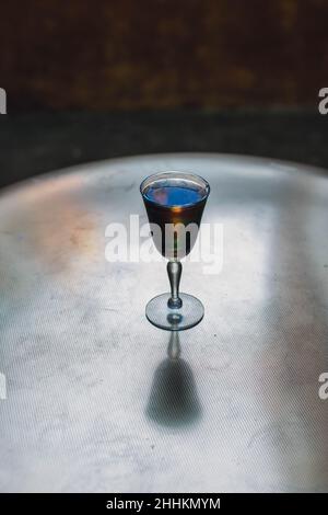 Schillerndes schwarzes Limonade-Cocktailgetränk am Abend mit goldenem Messingtisch Stockfoto