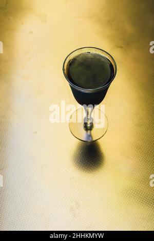 Schillerndes schwarzes Limonade-Cocktailgetränk am Abend mit goldenem Messingtisch Stockfoto