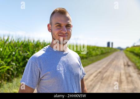 Stolzer Landwirt, der in einem Maisfeld auf die Kamera schaut. Hochwertige Fotos Stockfoto