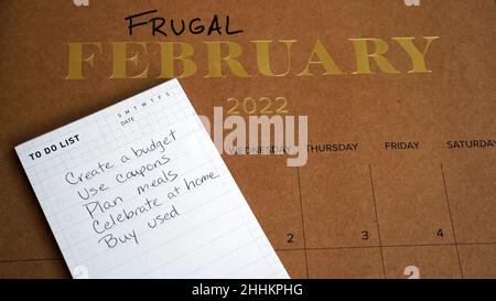 Sparsamer Februar auf dem Kalender zusammen mit einer Liste von Tipps geschrieben. Die Idee hinter Frugal February ist, zu versuchen, so billig wie möglich zu leben. Stockfoto