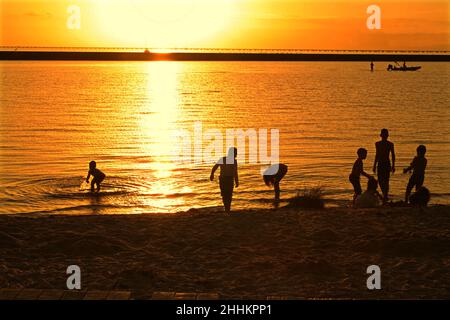 Kinder planschen im Lake Pontchartrain bei Sonnenuntergang Stockfoto