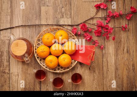 Teller mit Mandarinen, rotem Glückspilz und Teekocher für die chinesische Neujahrsfeier Stockfoto