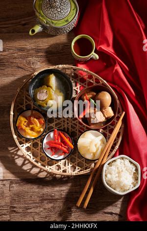 Gerichte für das chinesische Neujahr wie Reis, geschmortes Schweinefleisch mit Eiern, eingelegter Chilischote und Knoblauch und gefüllte Bittermelonensuppe Stockfoto