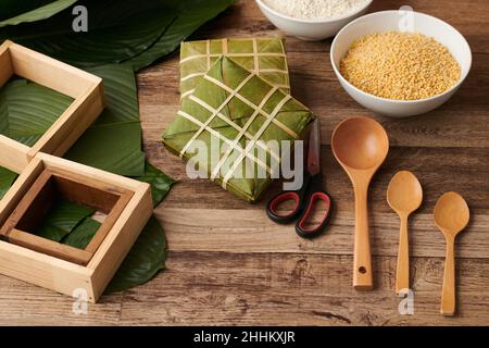 Gewickelte klebrige Reiskuchen, mit gelben Mungbohnen-Füllung, Holzlöffeln und Formen zum Kochen Stockfoto