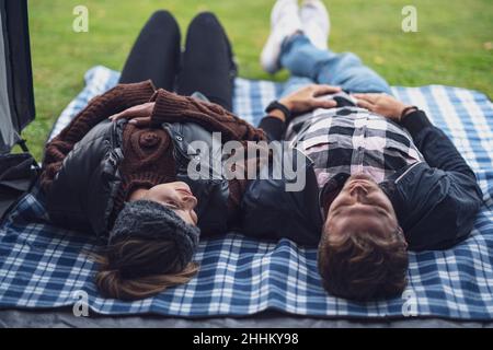 Junges nettes Paar, das Spaß auf dem Camping hat, im Zelt liegend Stockfoto
