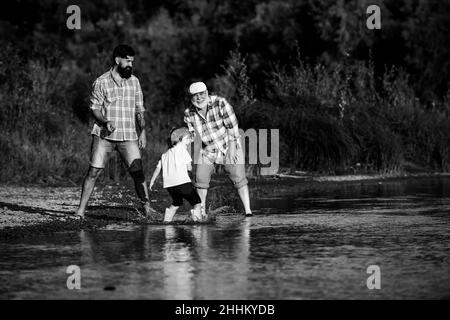 Familie in drei Generationen. Mit Papa und Großvater Steine überspringen. Drei verschiedene Generationen alt: Großvater Vater und Kind Sohn zusammen. Stockfoto