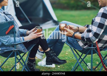 Junges nettes Paar, das auf Stühlen vor dem Zelt auf dem Camping sitzt Stockfoto