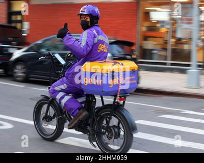 Ein Getir-Zusteller, der ein E-Bike fährt, gibt sich einen Daumen nach oben, als er in New York City vorbeifährt. Motion Blur. Sie sind ein sofortiger Bedarf an schnellem Handel Stockfoto