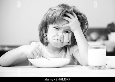 Unfokussierter kleiner Junge, der zum Mittagessen Suppe hat. Unglücklich kaukasischen Kind sitzen am Tisch in der Küche zu Hause haben keinen Appetit. Verärgert kleines Kind weigert sich zu essen Stockfoto