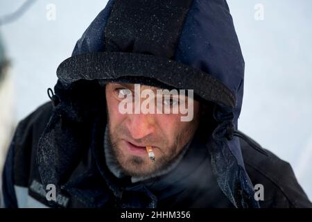 Nahaufnahme des Gesichts eines Arbeiters in einer blauen Jacke am Arbeitsplatz Stockfoto