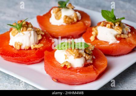 Traditionelles türkisches Quitten-Dessert. Die Quitte wird weich gekocht, darauf wird Sherbet gegossen und mit Rahm und Walnüssen serviert. Es ist einer der Th Stockfoto