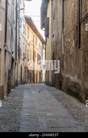 Stadtbild mit verwinkelten schmalen gepflasterten Gassen zwischen alten Gebäuden, aufgenommen im hellen Winterlicht in Rovato, Brescia, Italien Stockfoto