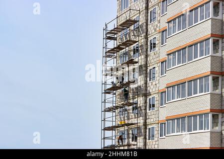 Bauherren arbeiten ohne Schutz, Versicherung. Bau eines mehrstöckigen Wohngebäudes. Bau- und Installationsarbeiten. Stockfoto