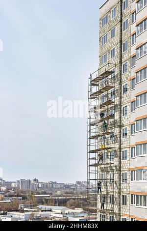 Bau- und Installationsarbeiten. Gefährliche Arbeit. Installation von Gerüsten. Bauherren arbeiten ohne Schutz, Versicherung. Stockfoto