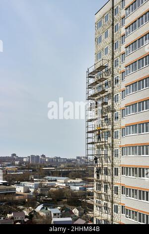 Bau- und Installationsarbeiten. Gefährliche Arbeit. Installation von Gerüsten. Bauherren arbeiten ohne Schutz, Versicherung. Stockfoto