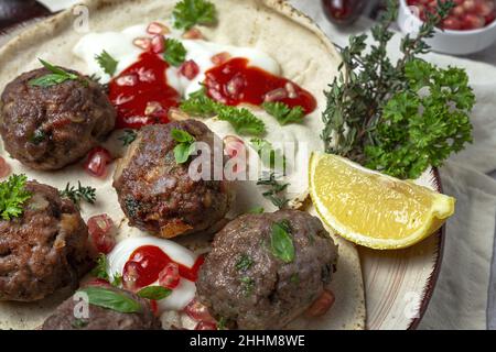 Traditionelle hausgemachte Fleisch- und Lammfleischbällchen mit arabischem Brot, Tomatensauce, Granatapfel und aromatischen Kräutern. Halal-Essen Stockfoto