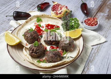 Traditionelle hausgemachte Fleisch- und Lammfleischbällchen mit arabischem Brot, Tomatensauce, Granatapfel und aromatischen Kräutern. Halal-Essen Stockfoto