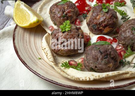 Traditionelle hausgemachte Fleisch- und Lammfleischbällchen mit arabischem Brot, Tomatensauce, Granatapfel und aromatischen Kräutern. Halal-Essen Stockfoto