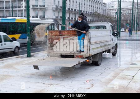 Mitarbeiter des technischen Dienstes der Gemeinde Athen wirft Anti-Eis-Salz, um die Eisbildung bei Schneefall in Athen zu verhindern Stockfoto