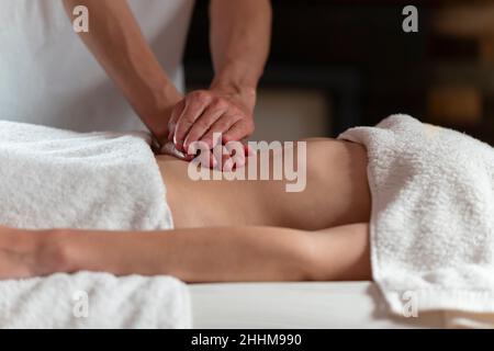 Eine Masseurin, die eine Ölmassage mit einer anderen Frau auf dem Bauch macht Stockfoto
