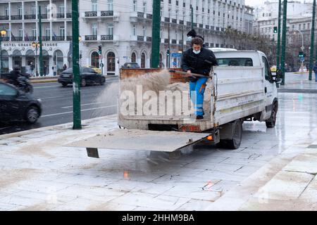 Mitarbeiter des technischen Dienstes der Gemeinde Athen wirft Anti-Eis-Salz, um die Eisbildung bei Schneefall in Athen zu verhindern Stockfoto