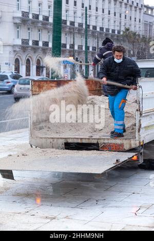 Mitarbeiter des technischen Dienstes der Gemeinde Athen wirft Anti-Eis-Salz, um die Eisbildung bei Schneefall in Athen zu verhindern Stockfoto