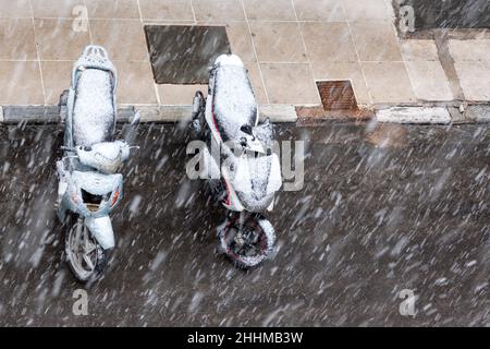 Motorräder, die bei Schneefall in Athen im Januar 24th 2022 geparkt wurden. Stockfoto