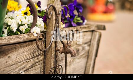 Wasserhahn als Deko in alt mit Rost auf einem Holzwagen mit gepflanzten Blumen. Detailreiche und strukturierte Dekoration Stockfoto