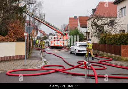 Markkleeberg, Deutschland. 25th Januar 2022. Mit einer Drehleiter löscht die Feuerwehr einen Brand im Dachstuhl eines leerstehenden Einfamilienhauses. Da man vermutete, dass sich Menschen im Gebäude befanden, kamen die Feuerwehr aus Leipzig und Markkleeberg mit zwei Drehleitern und insgesamt 30 Feuerwehrleuten an. Quelle: Jan Woitas/dpa-Zentralbild/dpa/Alamy Live News Stockfoto