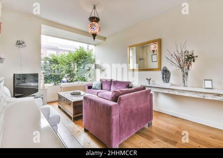 Charmantes Wohnzimmer mit purpurpurfarbenem Sofa aus Cord und Mosaik-Kronleuchter Stockfoto