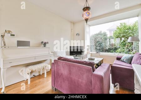 Charmantes Wohnzimmer mit purpurpurfarbenem Sofa aus Cord und Mosaik-Kronleuchter Stockfoto